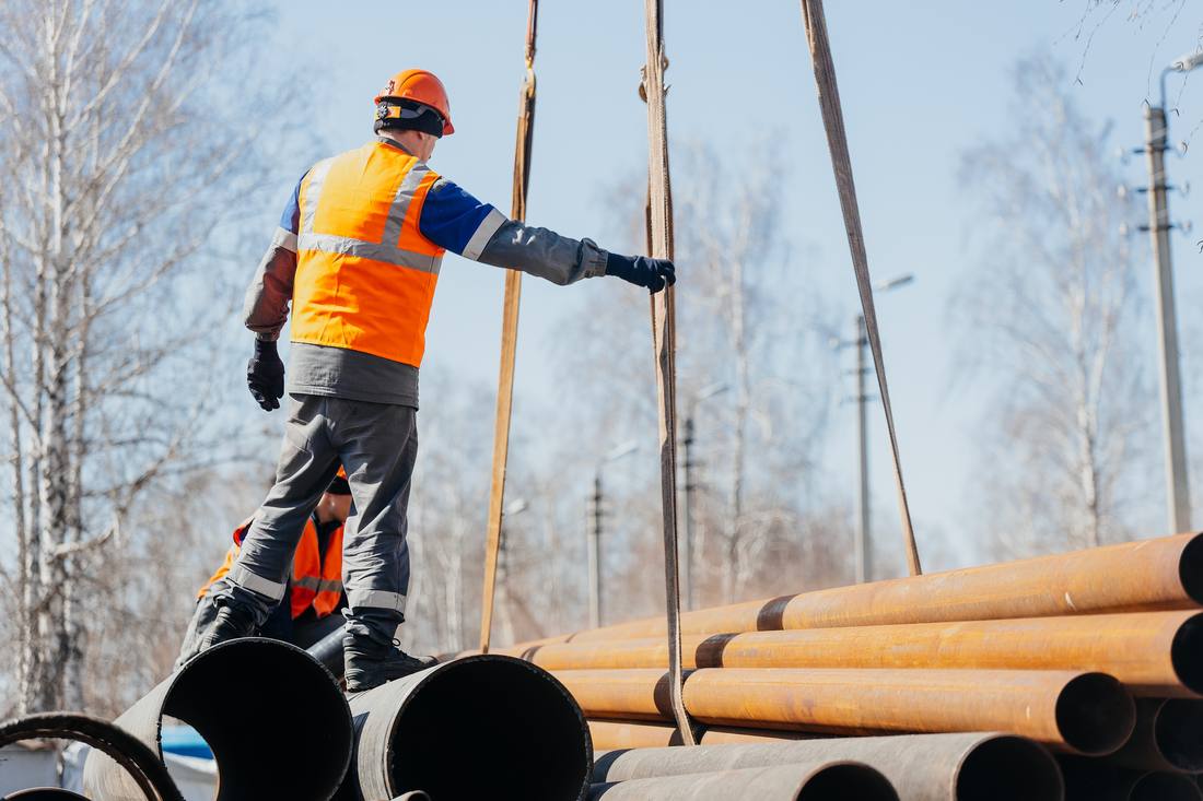 A worker in a hard hat inspecting industrial pipework.